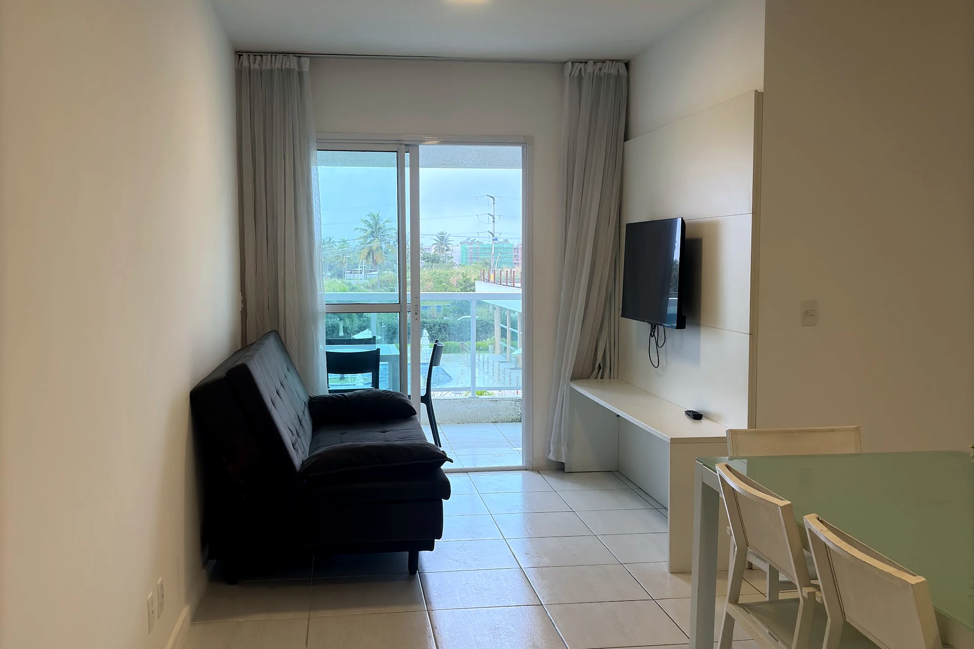 Sala do apartamento com sofá, mesa de jantar e porta para a varanda