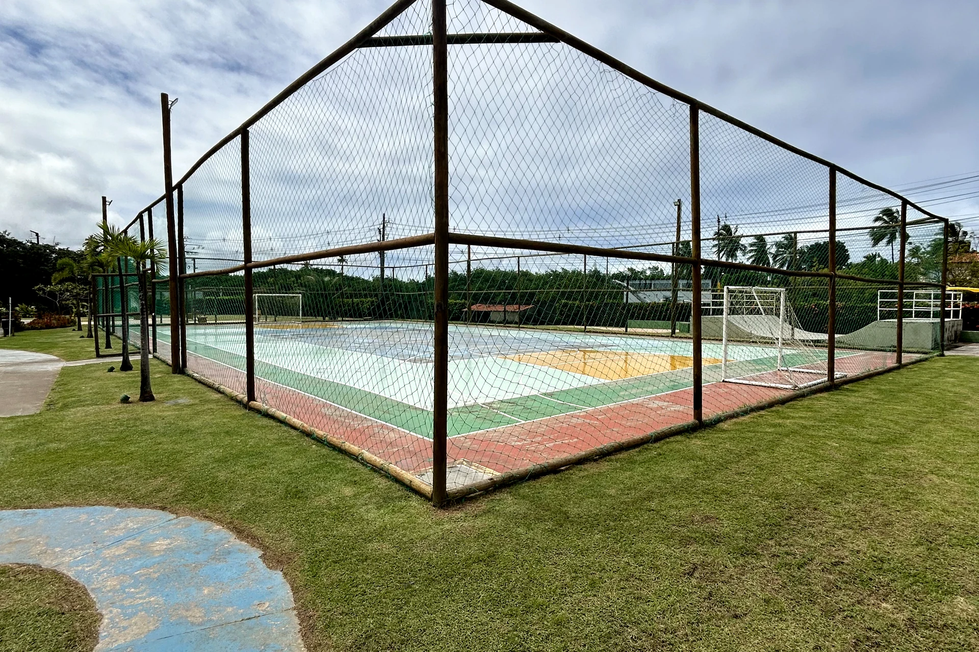 Quadra poliesportiva cercada, com piso pintado