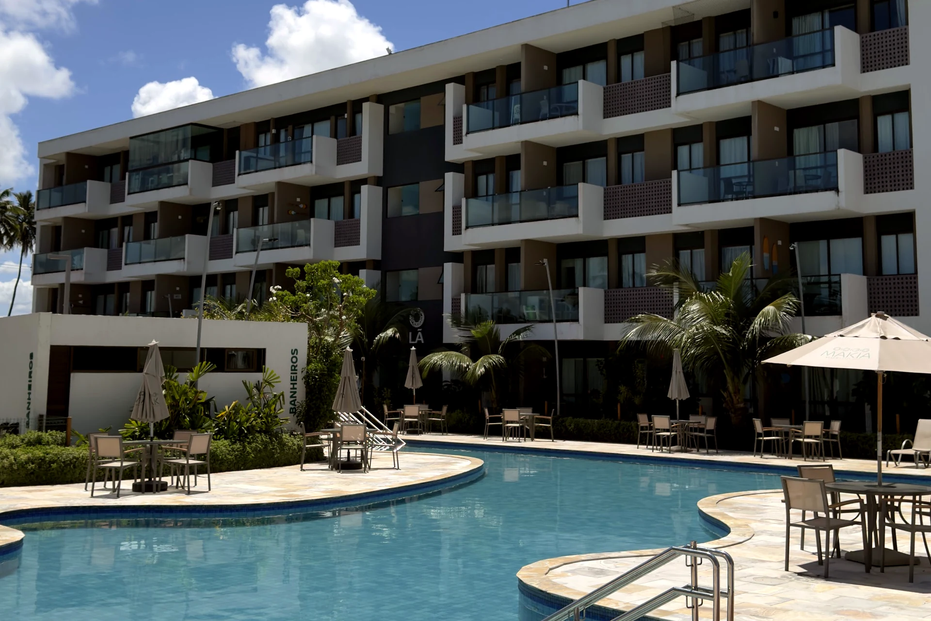 Piscina com espreguiçadeiras e guarda-sóis junto ao prédio