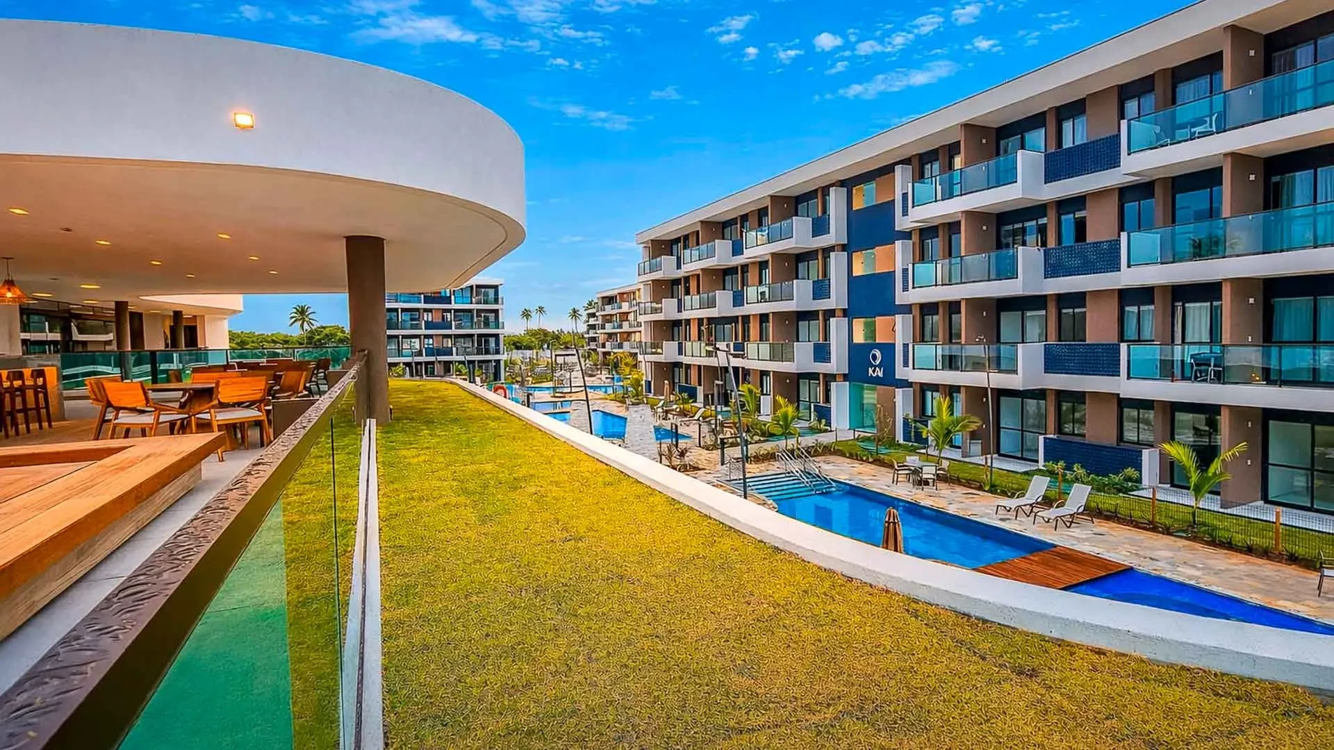 Rooftop do Makia com mesas, gramado e vista para a piscina e os apartamentos